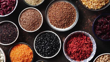 various superfoods in smal bowls on dark rusty background