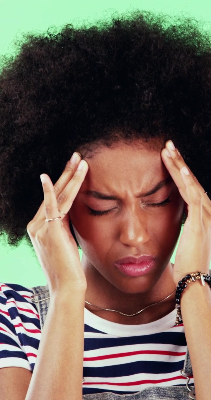 Young Woman Suffering From a Headache Against a Green Background