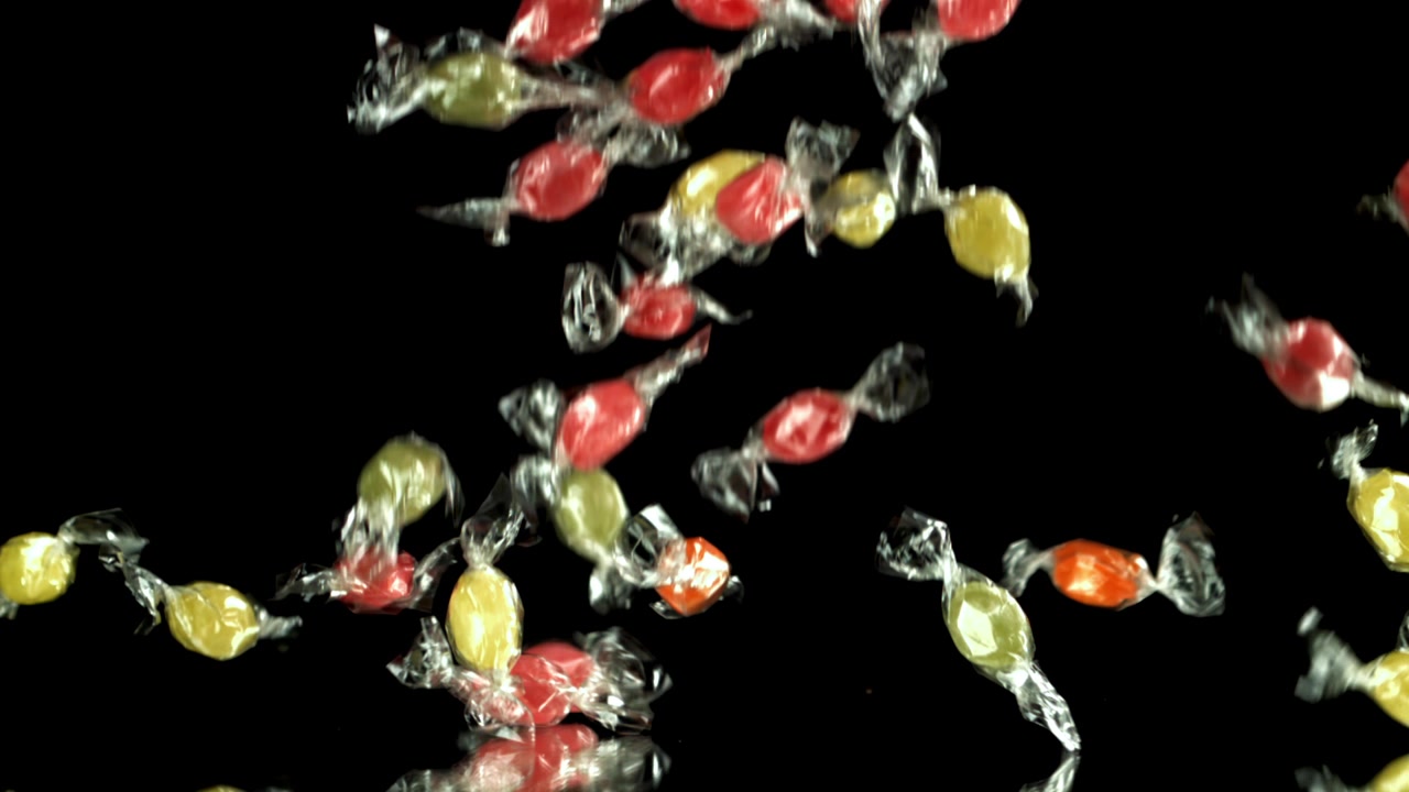 Colorful Wrapped Candies Falling on Black Background