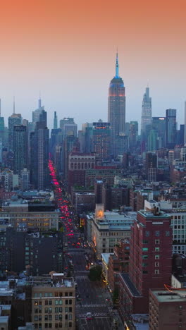 lovely view of city panorama at sunset. cars switched on red lights and move by the wide road of new york at the backdrop of pink sky. vertical video