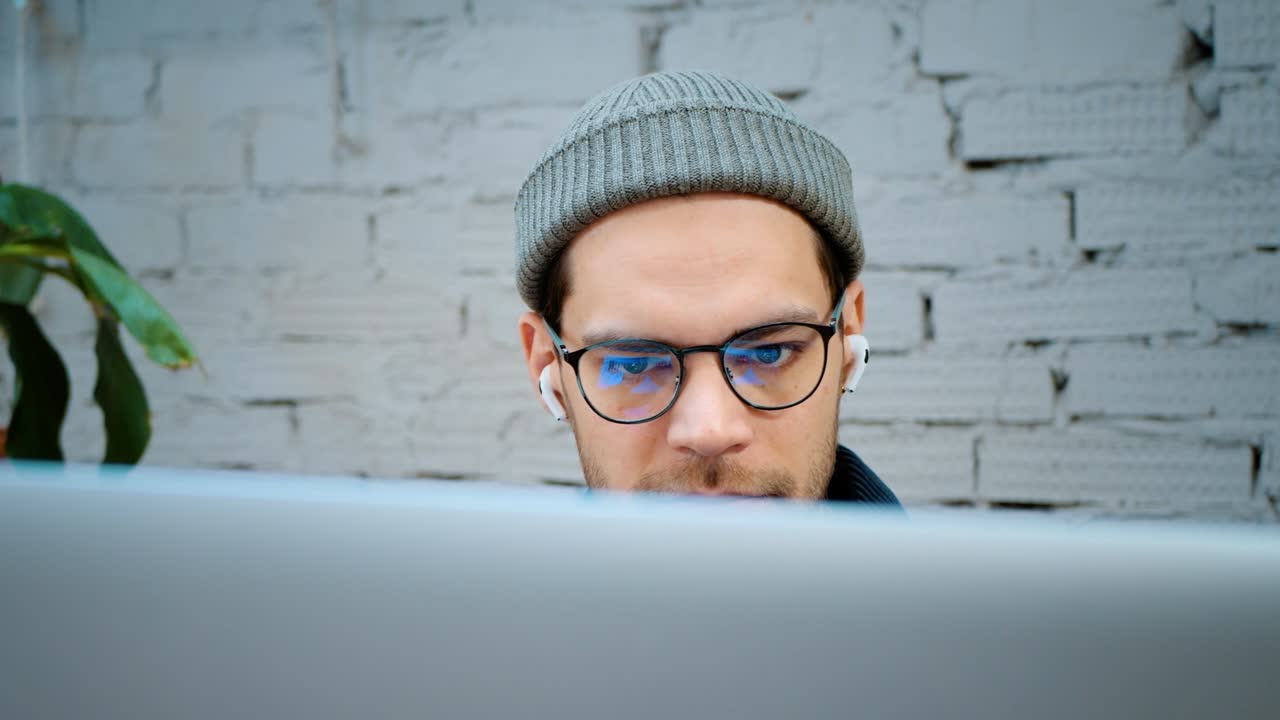 A man in a fashionable hat and glasses is looking for information on the Internet. close-up