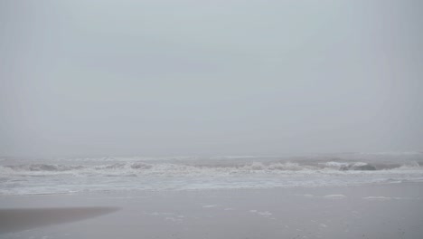 view from the beach of incoming waves during a super foggy morning