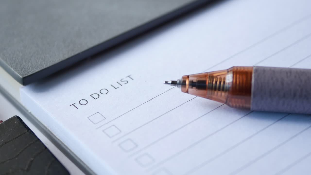 To do list in notebook with office suppliers on desk