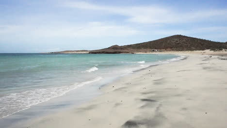 beautiful sea waves on the white sand beach with mountain in the background and blue sky day