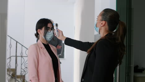 mujer caucásica con máscara facial comprobando la temperatura de los trabajadores