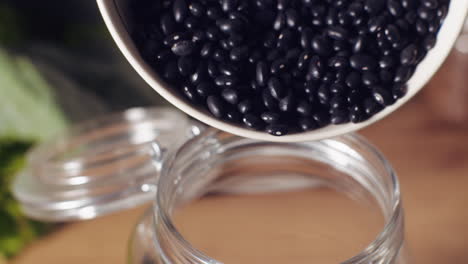 pouring black beans into a glass jar