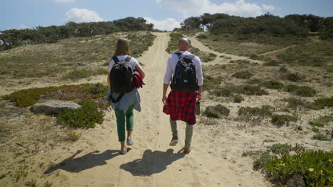 back view of couple with backpacks walking outdoor