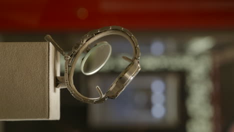 vertical side shot of elegant stainless steel luxury watch on sleek display stand at jewelry boutique