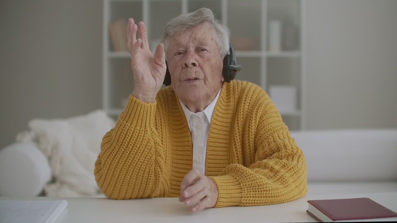 mujer de 60 años de edad hablando con la cámara de conferencia llamando en casa. sonriendo anciana madura señora adulta abuela hablar con la cámara web hacer video chat comunicarse en línea sentarse en el sofá vista de la cámara web