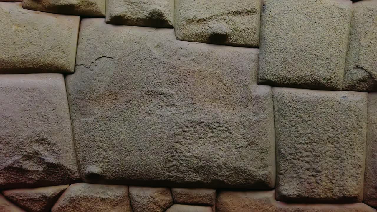 Detailed close-up of the precisely cut Twelve-Angled Stone, an iconic Inca masonry masterpiece in Cusco, Peru. Tilt up reveal shot