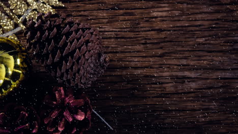 animation of christmas pine cones decoration with snow falling on wood