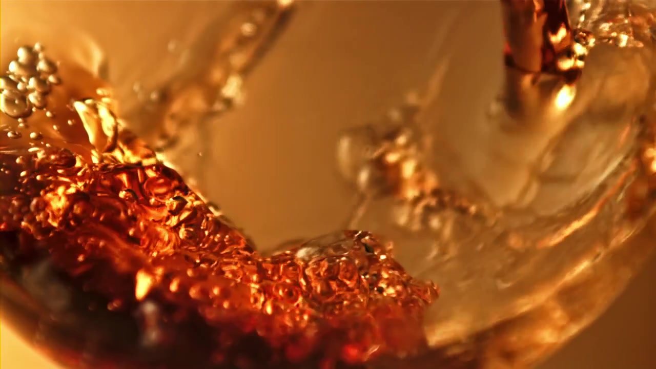 Slow Motion Pour of Amber Liquid into a Glass