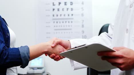 optometrista estrechando la mano con una paciente femenina