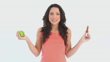 Mujer-Joven-Y-Atractiva-Eligiendo-Entre-Una-Manzana-Y-Una-Galleta