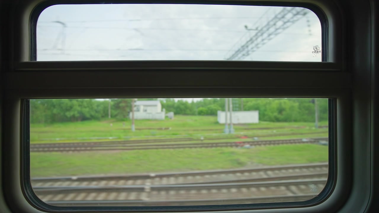 View from a Train Window of Passing Railway Tracks and Green Landscape