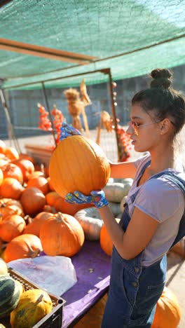 woman selecting a pumpkin at a fall market