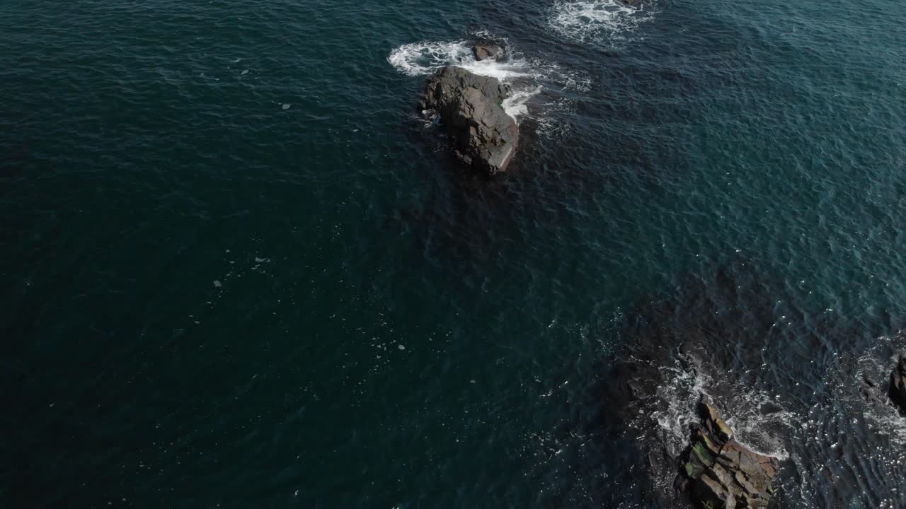 toma aérea sobre rocas en el mar, día soleado de verano