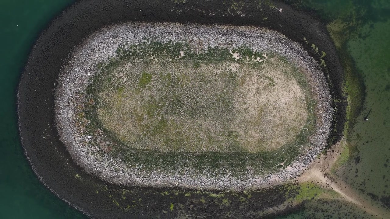 Letecký pohled na Schelphoek v Zeelandu, ukazující malý ostrov v zátoce obklopený pobřežní vodou, přírodou a charakteristickou holandskou pobřežní krajinou