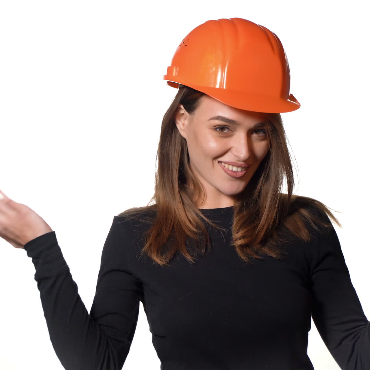 Beautiful woman in orange helmet and black golf is poses for the camera on a white background in the studio.