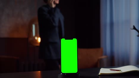 teléfono inteligente con pantalla verde en el entorno de la oficina