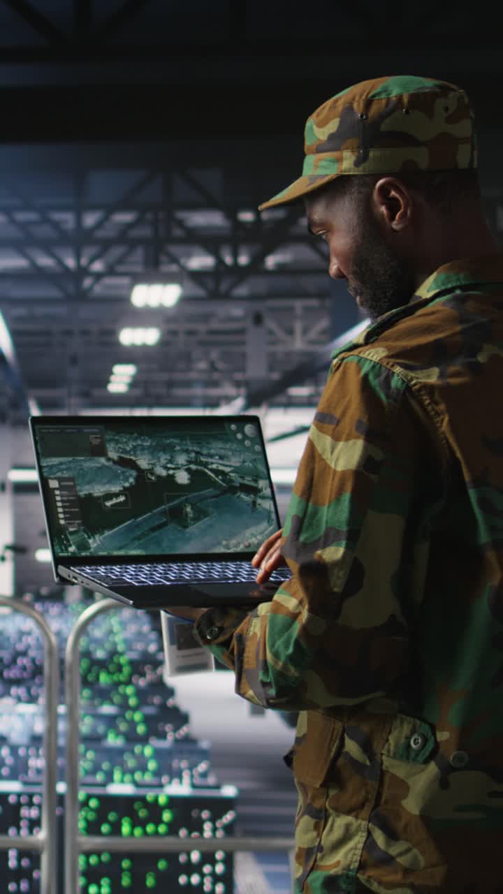 Vertical video Military technician in data center monitoring warfare drone telemetry on laptop