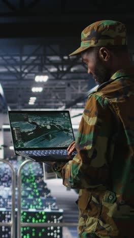 vertical video military technician in data center monitoring warfare drone telemetry on laptop