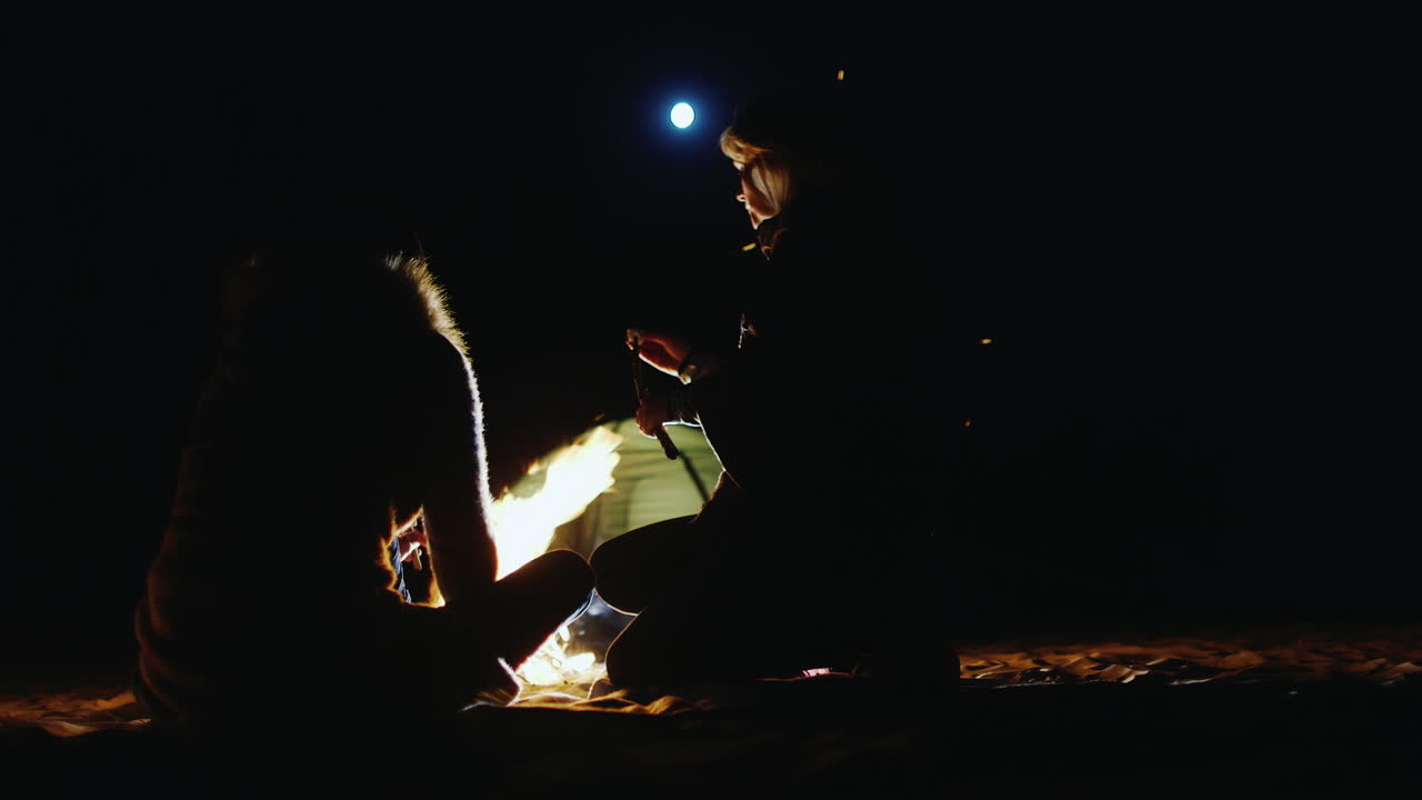 늦은 밤 모닥불 옆에서 마시멜로를 굽는 친구들