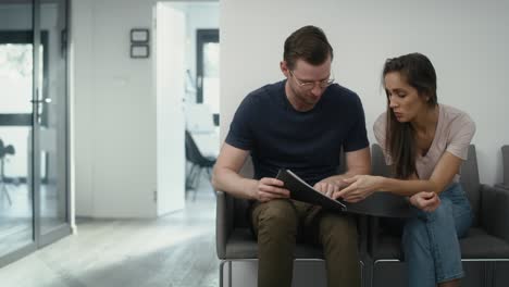 Caucasian-people-sitting-in-waiting-room-and-discussing-over-documents