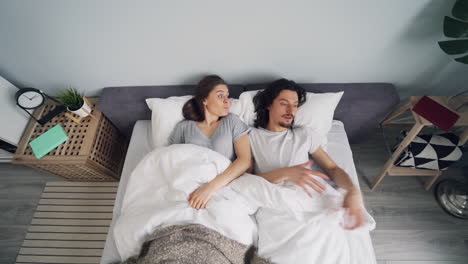 couple lying in bed, uncomfortable