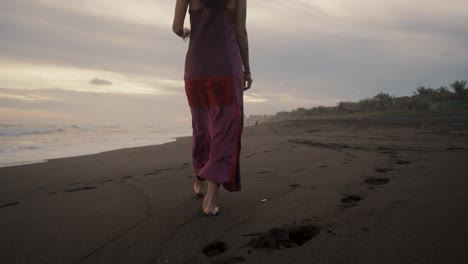slow motion of a woman on the sandy shore walking barefooted