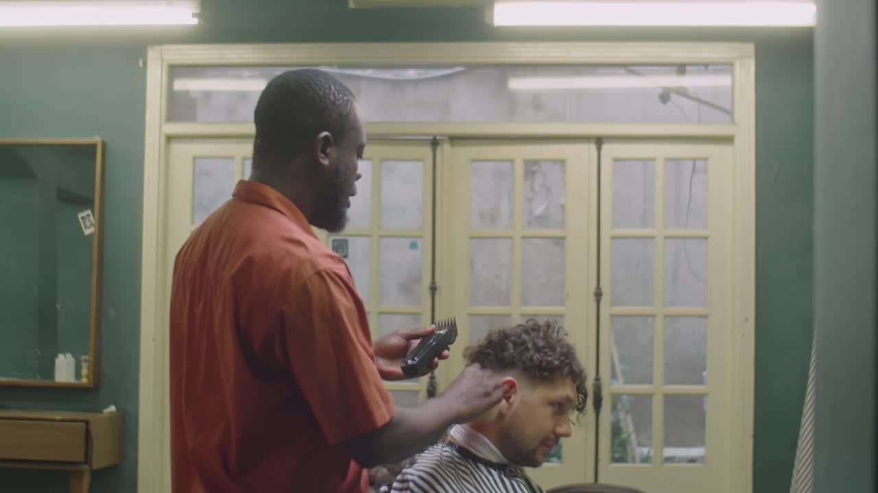Barber Giving Haircut to Male Client with Trimmer