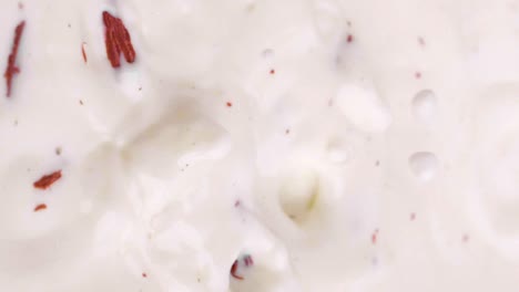 disparo vertical en cámara lenta de leche vegana con pedazos de chocolate cayendo en ella
