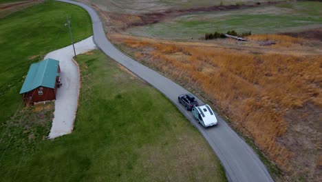 sports utility vehicle tows teardrop camper down winding country road_aerial drone in the spring