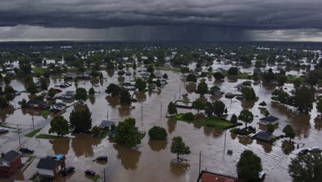 aerial view capturing devastating urban flooding, muddy waters consuming residential neighborhood, revealing widespread destruction during intense rainstorm