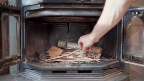 Man-Placing-Scraps-Of-Wood-Inside-The-Traditional-Heating-Stove