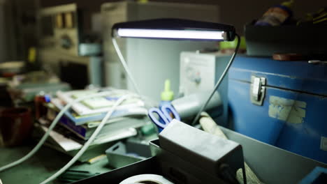 workspace cluttered with tools and a bright desk lamp illuminating the area