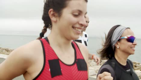 happy athletic friends jogging at seaside promenade