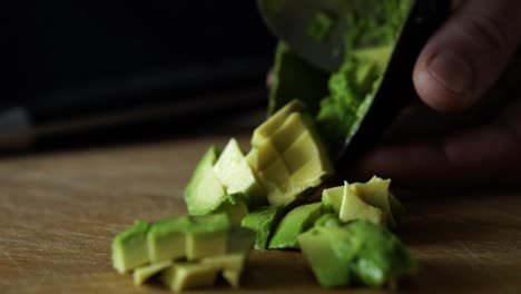 deslizando una cuchara metálica en rodajas de aguacate verde y sacándola de la piel