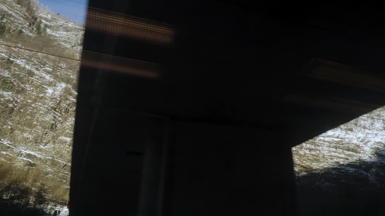 imágenes en movimiento del tren en marcha pasando por debajo de los puentes, mostrando montañas nevadas en un día soleado