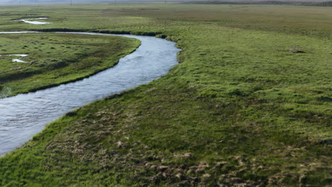 Winding-river-peacefully-meanders-through-lush-green-fields