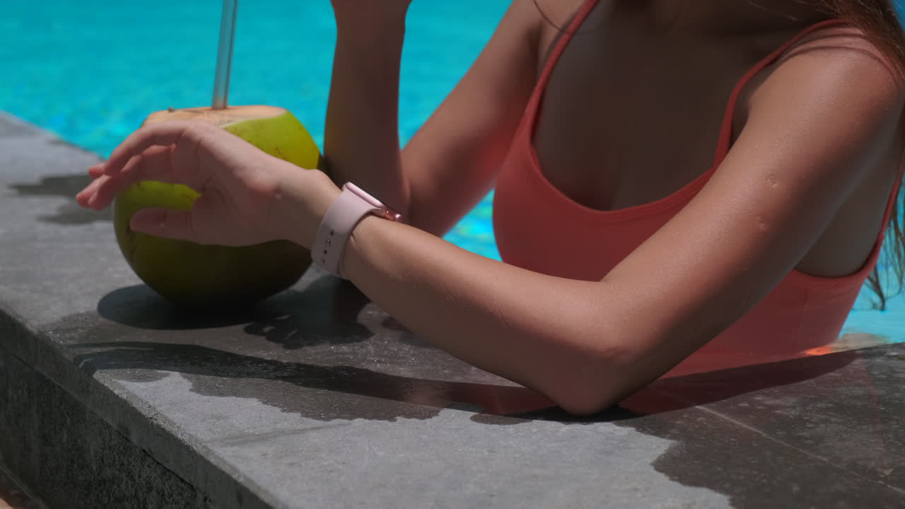 Woman relaxing by the pool with a coconut drink