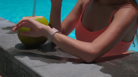 woman relaxing by the pool with a coconut drink