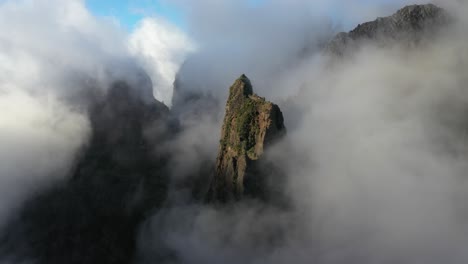 drone shot moving sideways among the foggy peaks of pico das torres in madeira