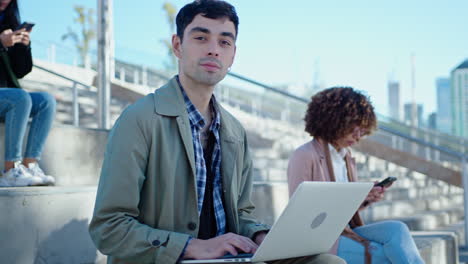 young businessman using laptop and posing on camera in the city