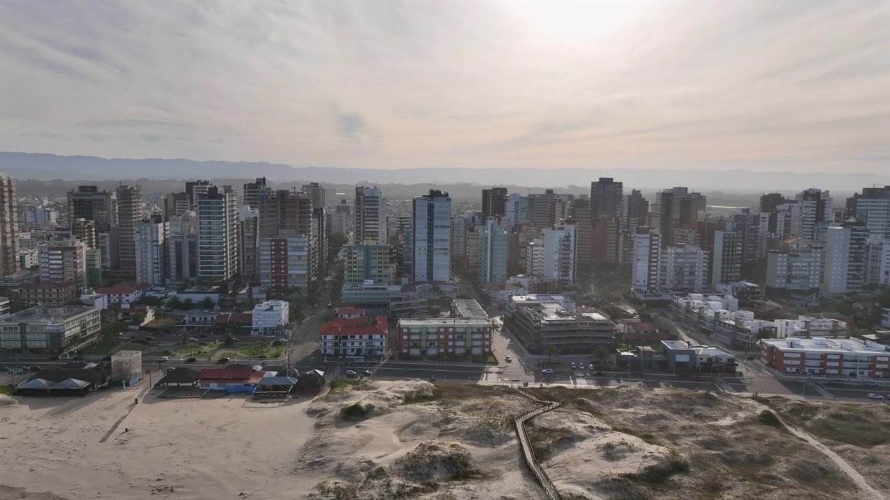 Paesaggio urbano costiero di Torres con panoramica da sinistra a destra che mostra grattacieli lungo una costa sabbiosa.