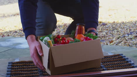 Primer-Plano-De-Un-Hombre-Caminando-Hasta-La-Puerta-De-La-Casa-Con-Una-Caja-De-Alimentos-E-Ingredientes-Frescos---Filmado-En-Cámara-Lenta