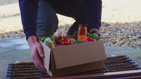primer plano de un hombre caminando hasta la puerta de la casa con una caja de comida fresca e ingredientes - filmado en cámara lenta
