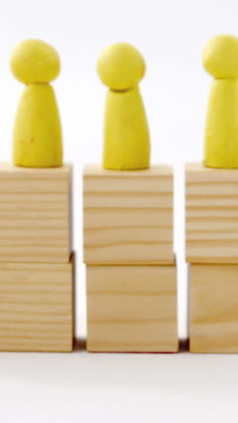 yellow figurines on wooden blocks in a row and red figurine fallen on ground