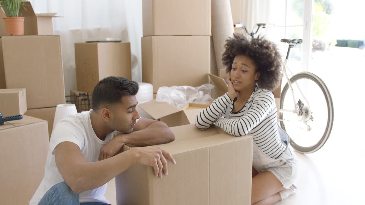 pareja exhausta tomando un descanso de empacar