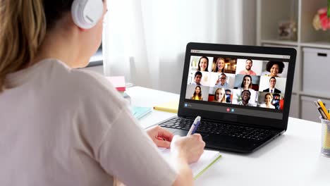 remote-job,-technology-and-people-concept--young-businesswoman-with-laptop-computer-and-papers-working-at-home-office-and-having-video-conference